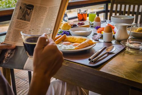 uma pessoa lendo um livro à mesa com comida em The L Resort, Krabi em Praia de Ao Nang