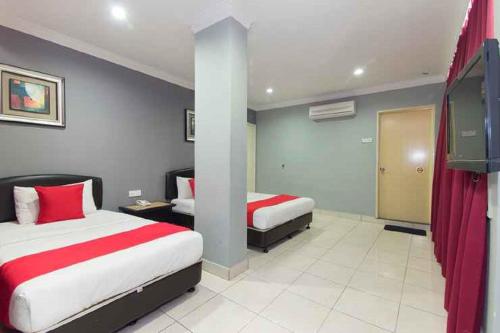 a hotel room with two beds with red sheets at Puteri Ampang Hotel in Ampang