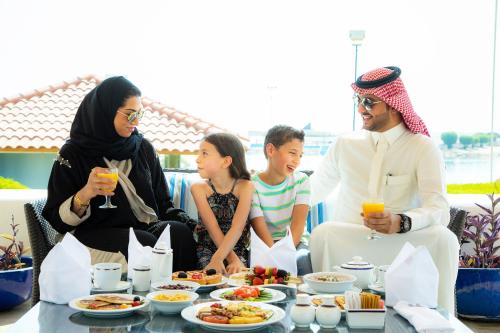 Un groupe de personnes assises autour d'une table avec de la nourriture dans l'établissement InterContinental Al Jubail Resort, à Al-Jubayl