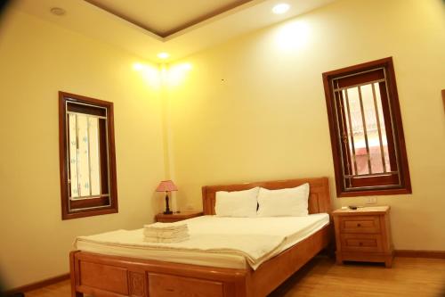 a bedroom with a bed and two windows at Duong Ha Hotel in Cao Bằng