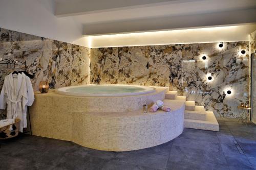 a large bathroom with a tub and a stone wall at Hôtel Fesch & Spa in Ajaccio