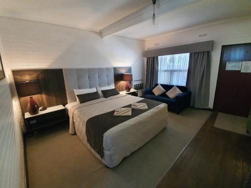 een hotelkamer met een groot bed en een bank bij Angaston Vineyards Motel in Angaston