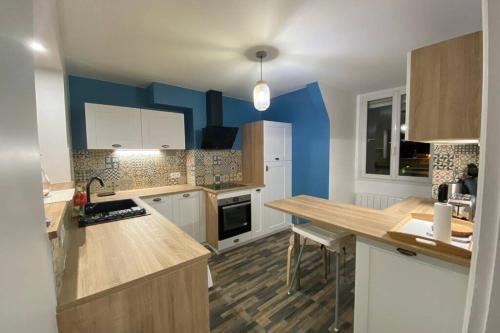 - une cuisine avec des placards blancs et des murs bleus dans l'établissement Face mer - 95m2 - 3ch vue mer - 8 personnes, à Saint-Valery-en-Caux