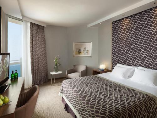 テルアビブにあるダン パノラマ テルアビブホテルの大きなベッドとデスクが備わるホテルルームです。