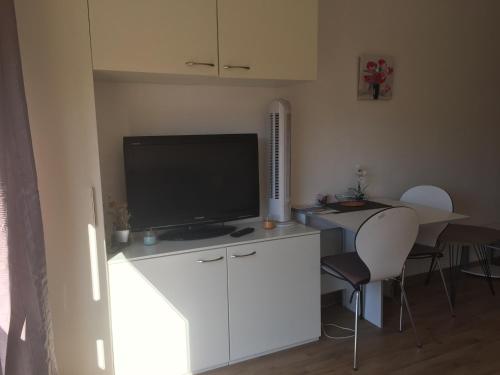 Il comprend un salon doté d'une télévision et d'une table avec des chaises. dans l'établissement Calvi au soleil, à Calvi