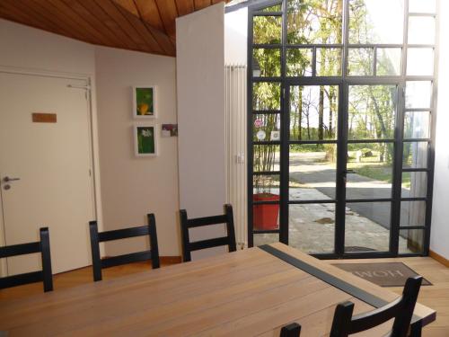 ein Esszimmer mit einem Tisch und einer großen Glastür in der Unterkunft Le bois du drillais in La Gaubretière