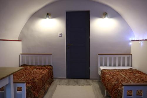 two beds in a room with a door and two lights at Levendula vendégház in Nemesvita