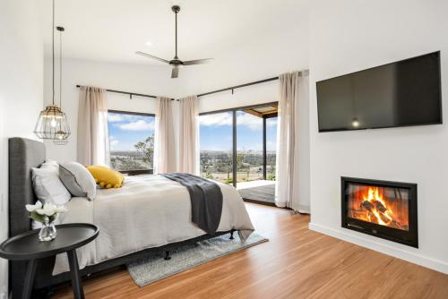 1 dormitorio con 1 cama con chimenea y TV en Old Bull Creek Luxury Retreat, en Strathalbyn