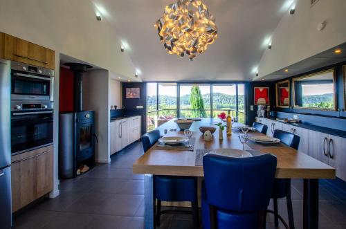 a kitchen with a large wooden table and blue chairs at Maison Anne Fouquet in La Roque-Gageac