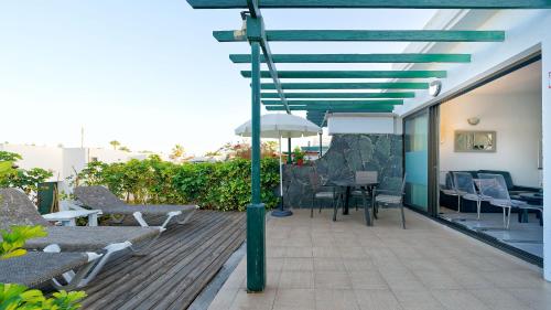 a deck with a table and chairs and an umbrella at Maspalomas Lago Canary Sunset in Maspalomas