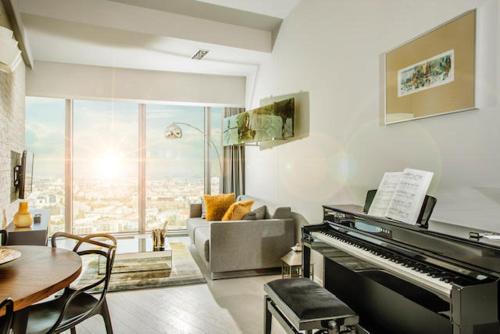 a living room with a piano and a couch and a table at 30th+ Floor Apartments in Sky Tower in Wrocław