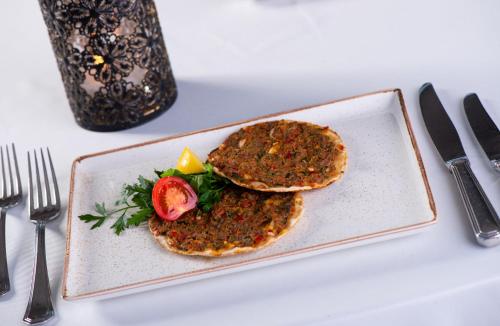 a plate with two pancakes with a tomato on it at Wellborn Luxury Hotel in Kocaeli