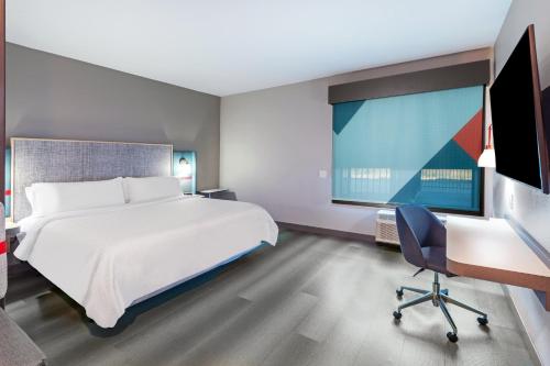 a bedroom with a bed and a desk and a tv at avid hotel - Bentonville - Rogers by IHG in Bentonville