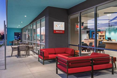a store with a red couch and tables and chairs at avid hotel - Bentonville - Rogers by IHG in Bentonville