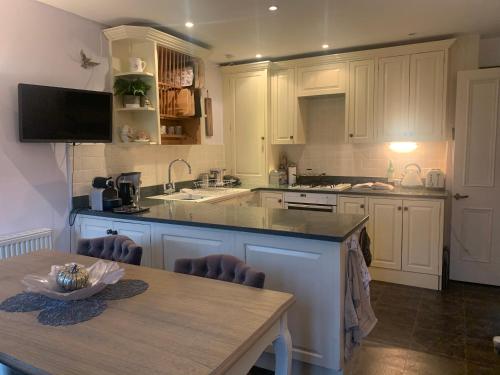 a kitchen with white cabinets and a table and a sink at Luxury barn conversion near Salcombe & Kingsbridge, South Devon in Kingsbridge