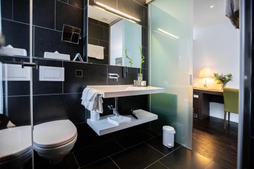 a bathroom with a toilet and a sink at Mercure Chur City West in Chur
