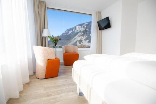 1 dormitorio con 1 cama, 2 sillas y ventana en Mercure Chur City West, en Chur