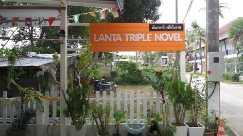 ein Zeichen, dass das lessianische Trippe Noveket neben Pflanzen in der Unterkunft Lanta Triple Novel in Ko Lanta