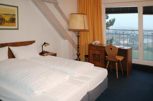 a bedroom with a bed and a desk and a window at Burghotel Volmarstein in Wetter