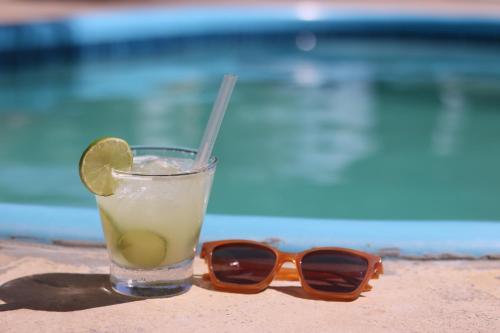 a drink with a slice of lime and a pair of sunglasses at Pousada Lagunas in Ponta do Anel