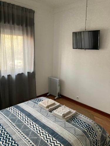 1 dormitorio con 1 cama y TV en la pared en Buddies Family Room, en Aveiro