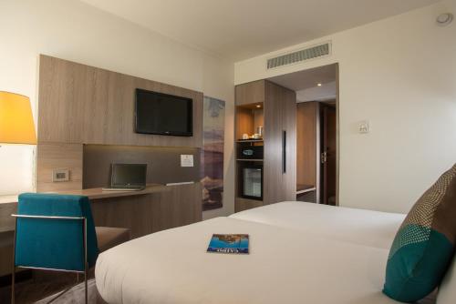 a hotel room with two beds and a television at Novotel Cairo Airport in Cairo