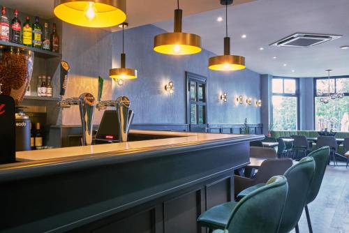 a bar in a restaurant with chairs and lights at Alp de Veenen Hotel in Amstelveen