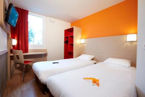 a hotel room with two beds and a desk and a window at Première Classe Roissy - Aéroport CDG - Le Mesnil-Amelot in Le Mesnil-Amelot