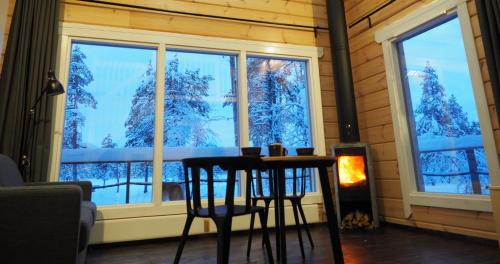 einen Tisch und Stühle vor einem Fenster mit Schnee in der Unterkunft LapinTintti Eco-Cabin in Inari in Inari