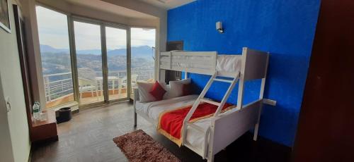 a bedroom with a blue wall and a bunk bed at amravati resort in Solan