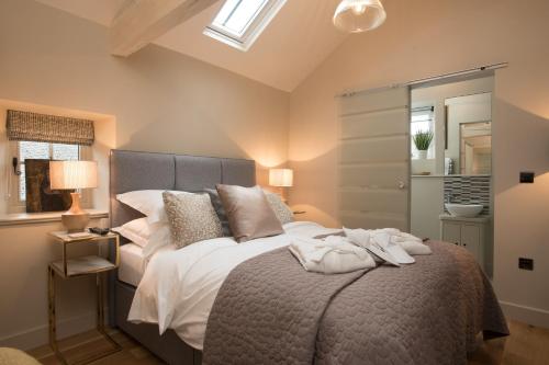 um quarto com uma cama grande com lençóis brancos e almofadas em Stownes em Stow on the Wold