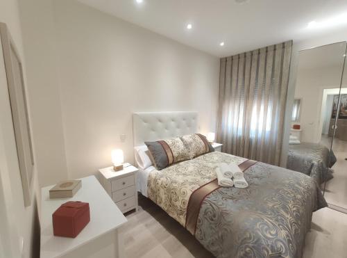 a white bedroom with a bed and a mirror at Apartamento Rosa Park in Toledo