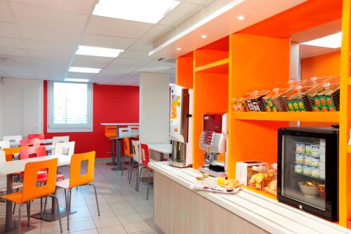 a fast food restaurant with orange walls and tables and chairs at Première Classe Roissy - Aéroport CDG - Le Mesnil-Amelot in Le Mesnil-Amelot