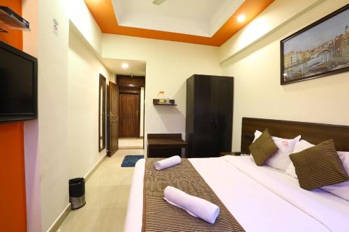 a bedroom with a bed with purple pillows on it at Hotel Sona in Panaji