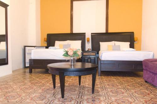 una habitación de hotel con 2 camas y una mesa con flores en Hotel Real San Juan Suites, en Mérida