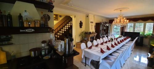 a dining room with a long table with white chairs at Noclegi Sylana in Kobyłka