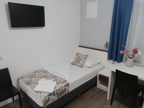 a small bedroom with a bed and a desk with a television at Hotel Dina in Međugorje