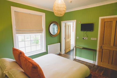 a green bedroom with a bed and a television at The Kings Arms - Fleggburgh in Burgh Saint Margaret