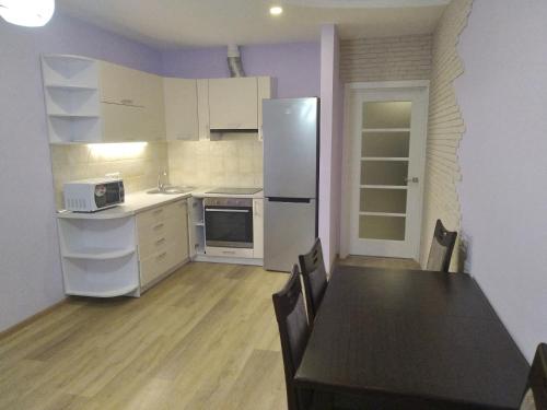 eine Küche mit einem Tisch und einem Kühlschrank in der Unterkunft Современная квартира в новом комплексе возле Днепра in Tscherkassy