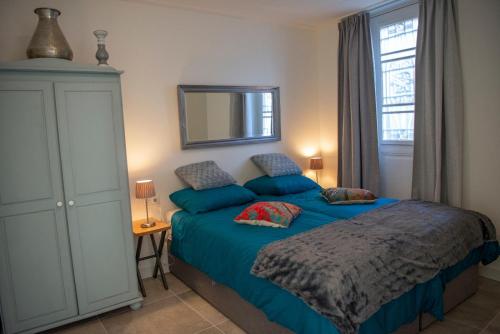een slaapkamer met een blauw bed en een spiegel bij Studio Augusta in Den Burg