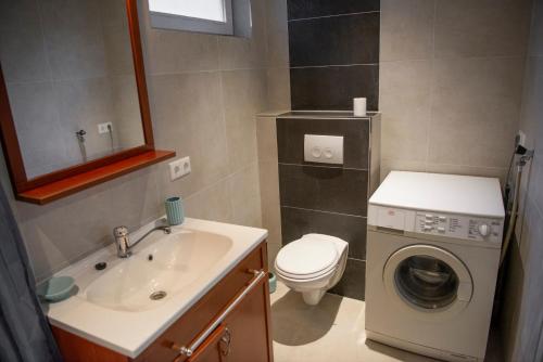 een badkamer met een wastafel en een wasmachine bij Studio Augusta in Den Burg