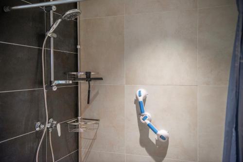 El baño incluye ducha con cabezal de ducha azul y blanco. en Studio Augusta, en Den Burg