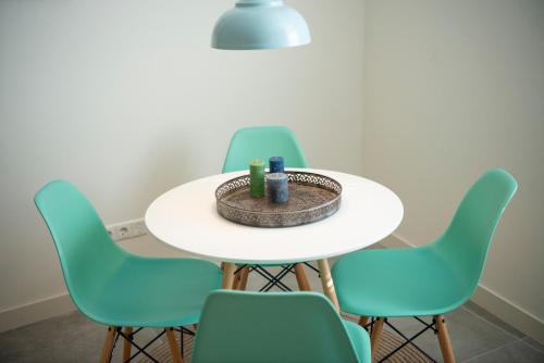 een witte tafel met groene stoelen eromheen bij Studio Augusta in Den Burg