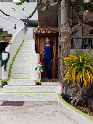 a woman standing in the doorway of a building with a dog at Hostal Cann's House in Puerto Baquerizo Moreno