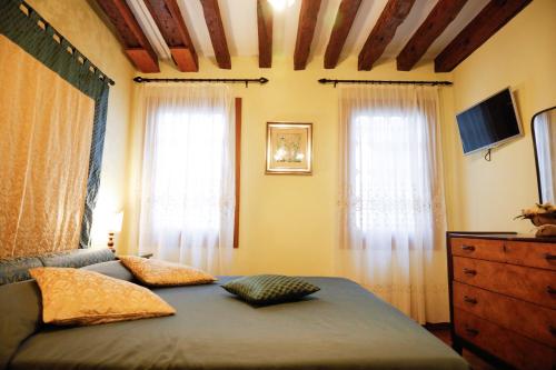 ein Schlafzimmer mit einem Bett, einer Kommode und zwei Fenstern in der Unterkunft Appartamento San Marco Frezzaria in Venedig
