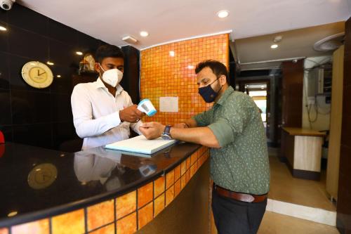 two men wearing face masks standing at a counter at Hotel Sona in Panaji