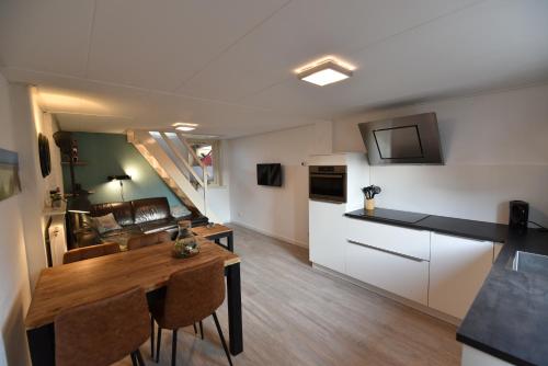 a kitchen and living room with a table and a kitchen and a dining room at Appartement Tjerk in Hollum