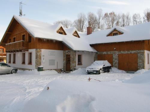 a house with a car parked in the snow at Apartmány U Švýcarského dvora in Janske Lazne