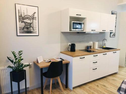 a kitchen with white cabinets and a table with a microwave at Property Apart - Soft Lofty Legnicka Centrum in Wrocław