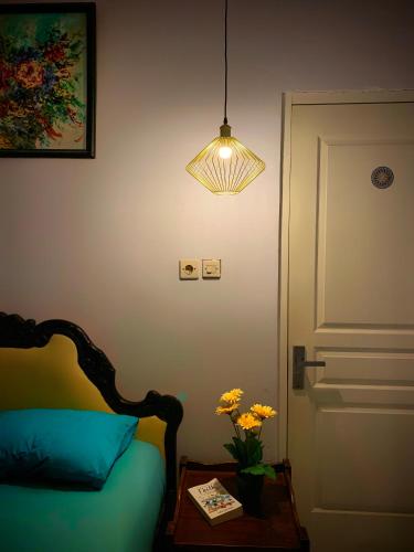 a bedroom with a bed and a lamp and a table with flowers at Rumah Sorai in Batu